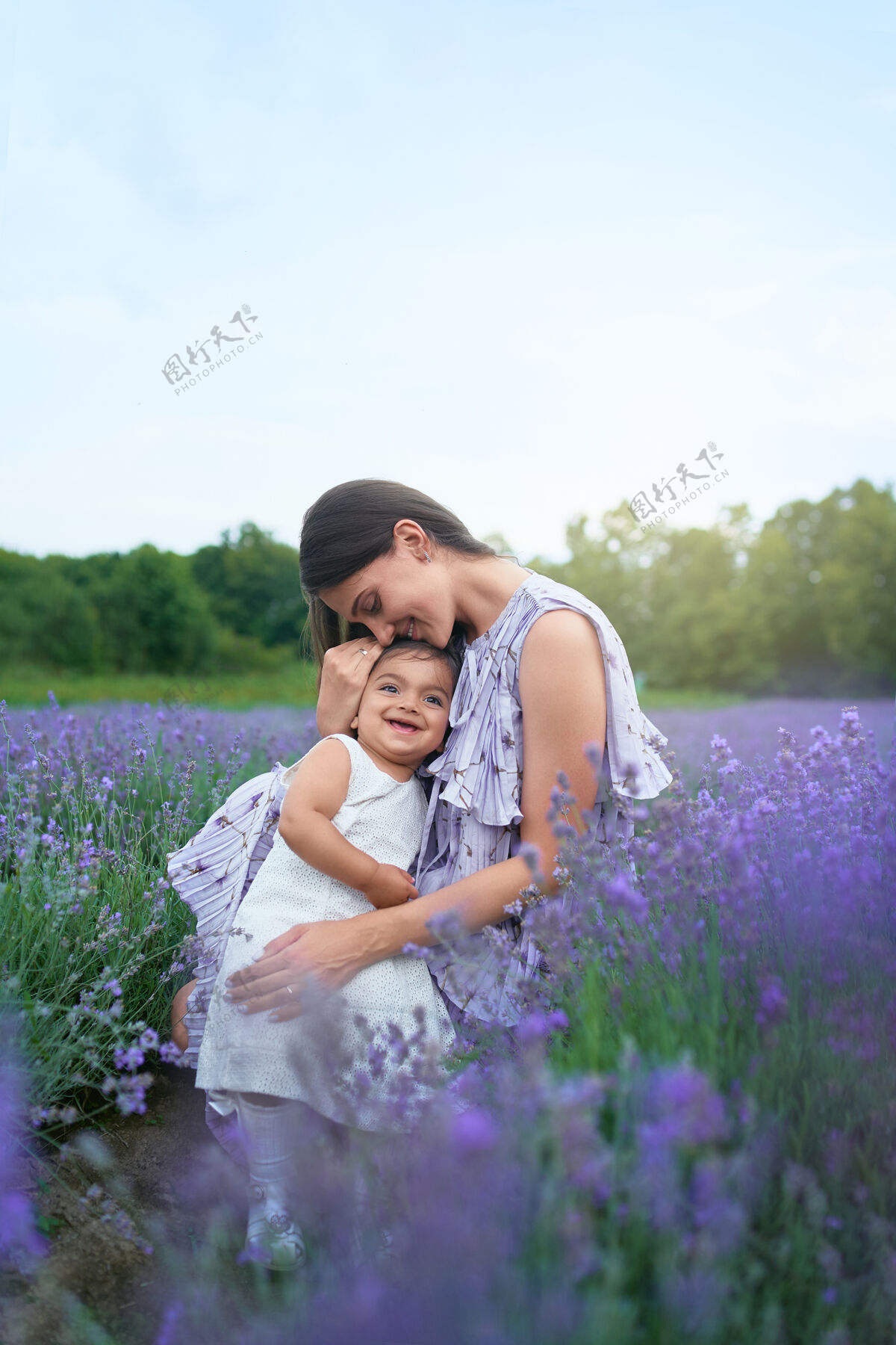 孩子快乐的年轻妈妈在薰衣草地里拥抱着孩子薰衣草童年生活