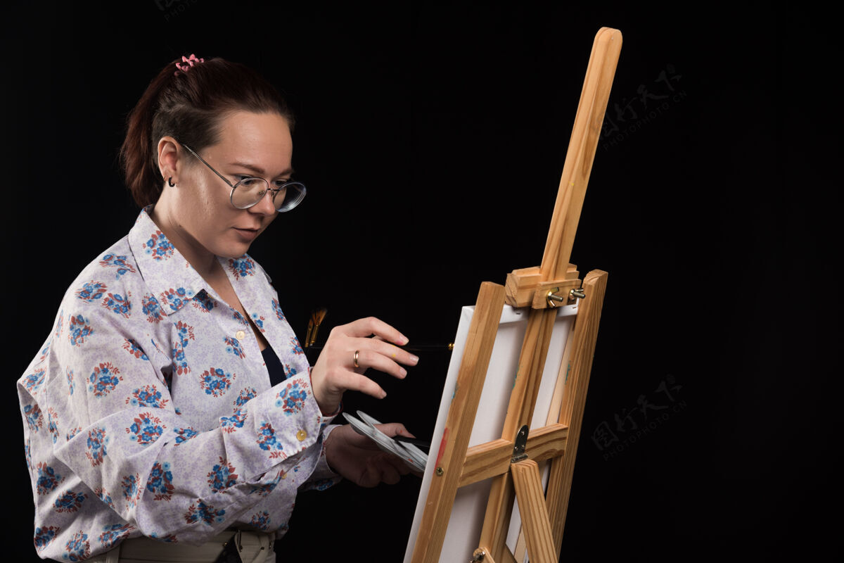 铅笔女画家用黑色的铅笔在画布上画画年轻绘画画布