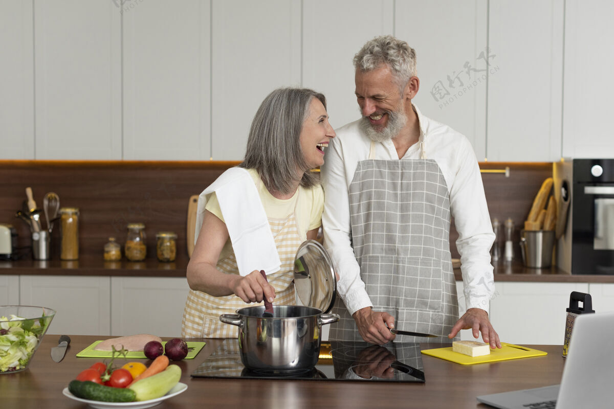 老年人老两口在厨房用笔记本电脑上烹饪课里面家庭水平