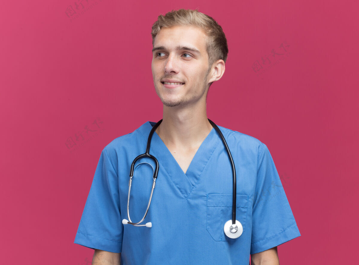 制服微笑着看着身边穿着医生制服的年轻男医生 听诊器隔离在粉红色的墙上 留有复印空间感觉人人