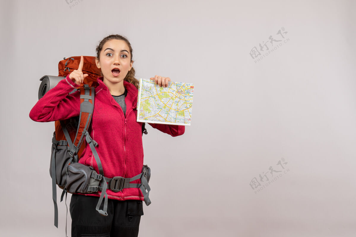 人正面图年轻的旅行者拿着大背包拿着地图手指向上漂亮旅行者年轻的旅行者