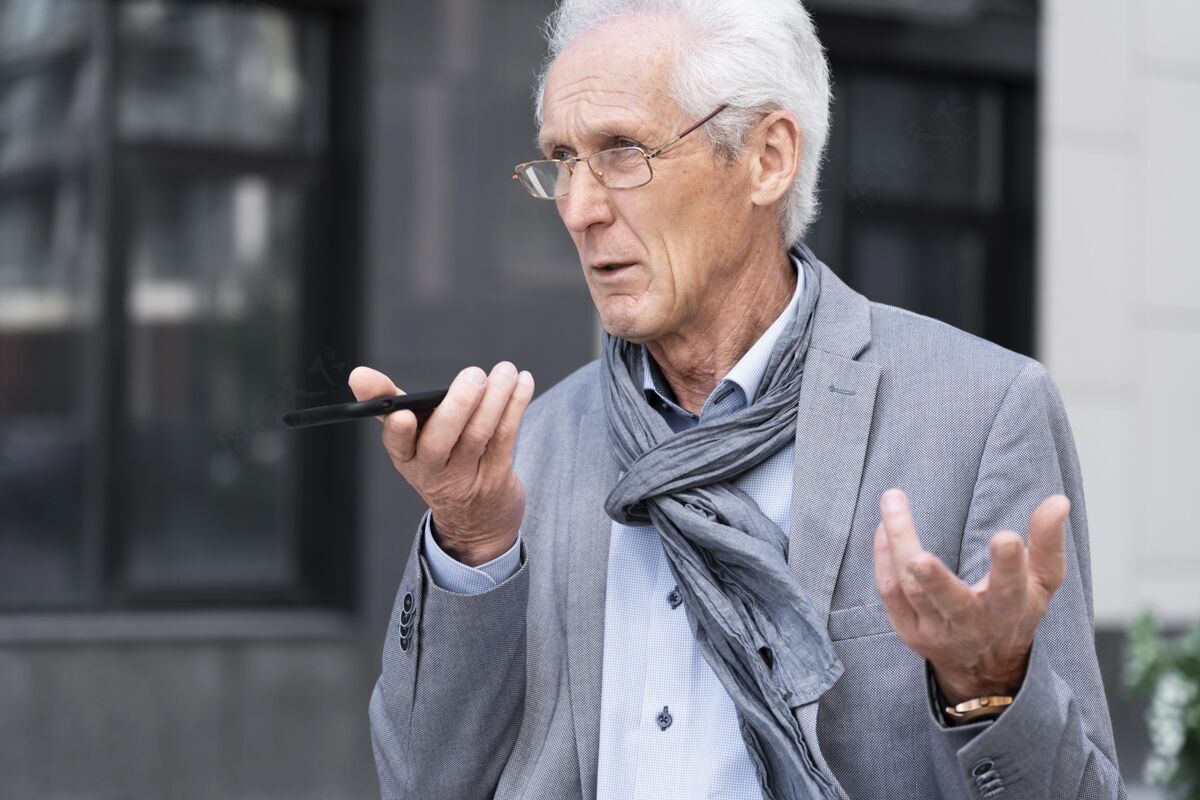 男性城里的一个老男人在用智能手机聊天户外老年老年人