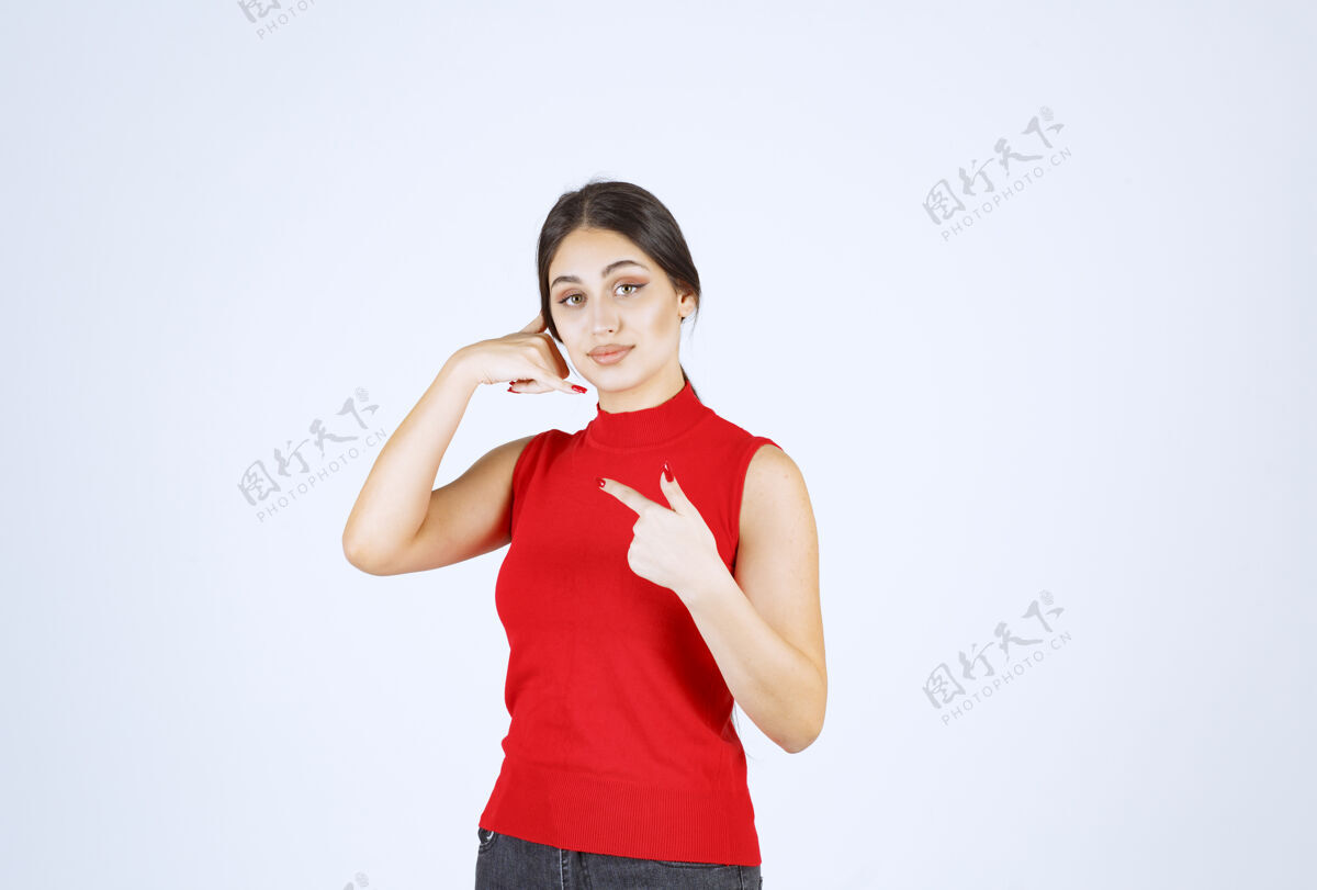 姿势穿红衬衫的女孩指着左边雇员年轻人服装
