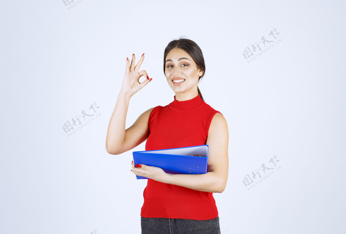 人类穿着红衬衫的女孩手里拿着一个蓝色的商业文件夹成人服装模特