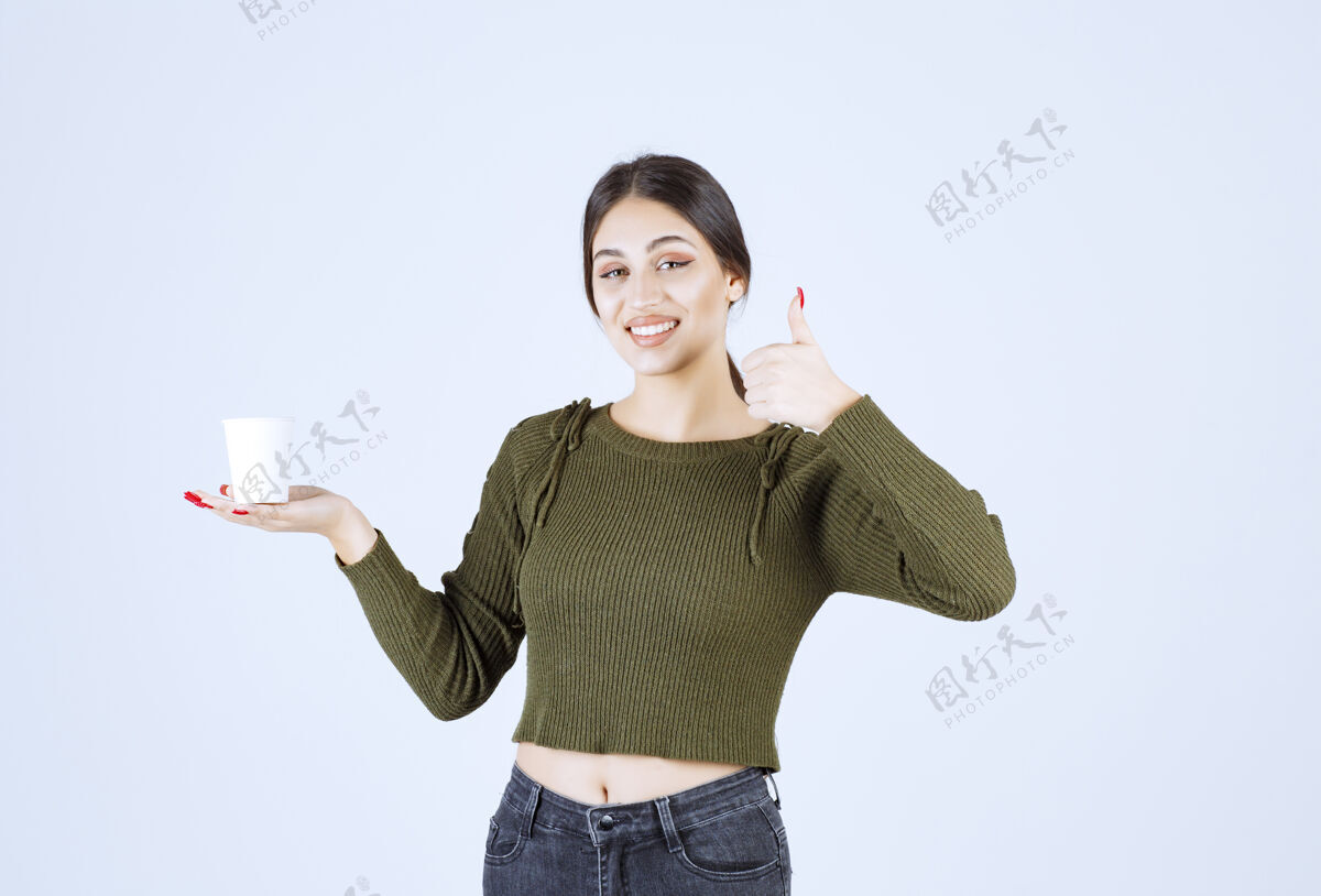 年轻黑发女人拿着塑料杯竖起大拇指杯子女人黑发