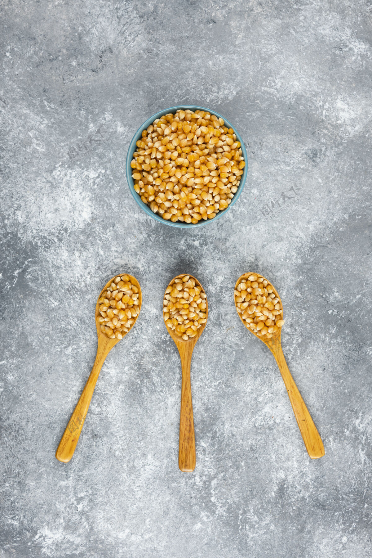 天然大理石桌上放着一碗玉米粒谷物爆米花种子