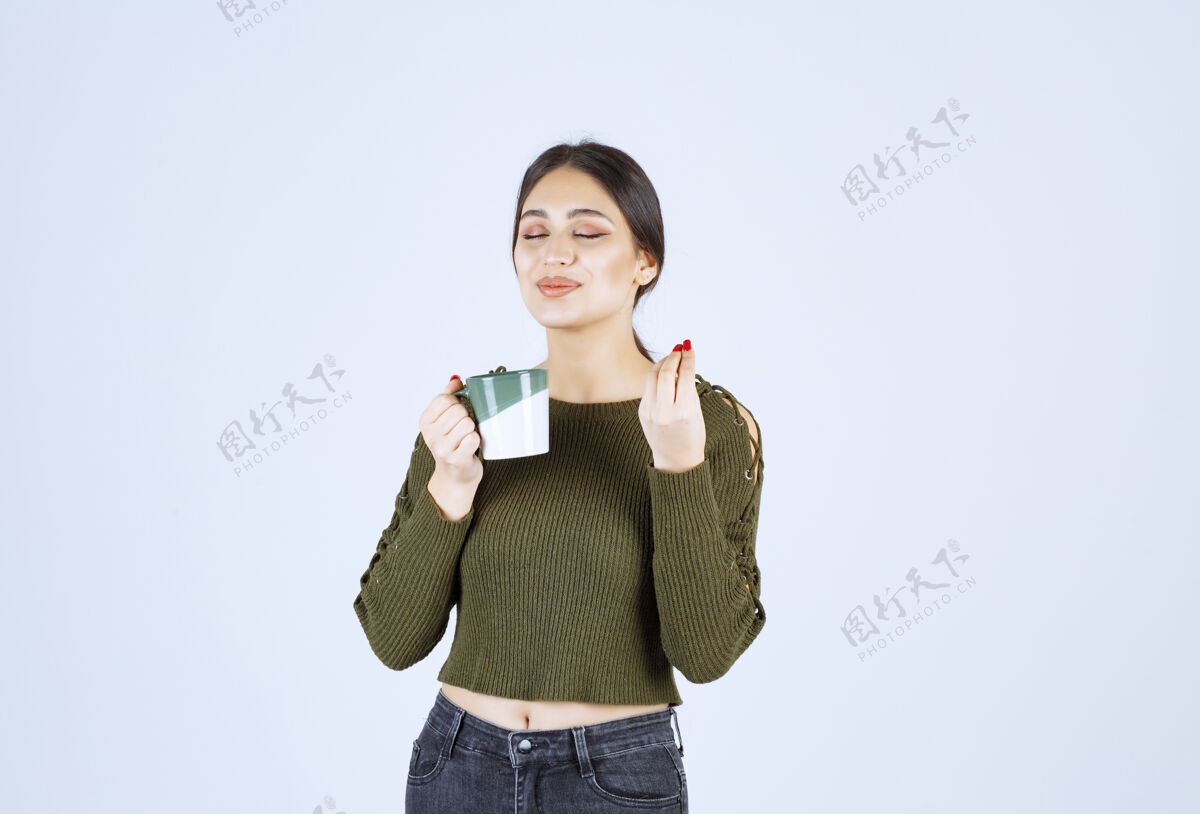 喝的一个年轻漂亮的女模特在喝一杯热茶杯子女人摆姿势