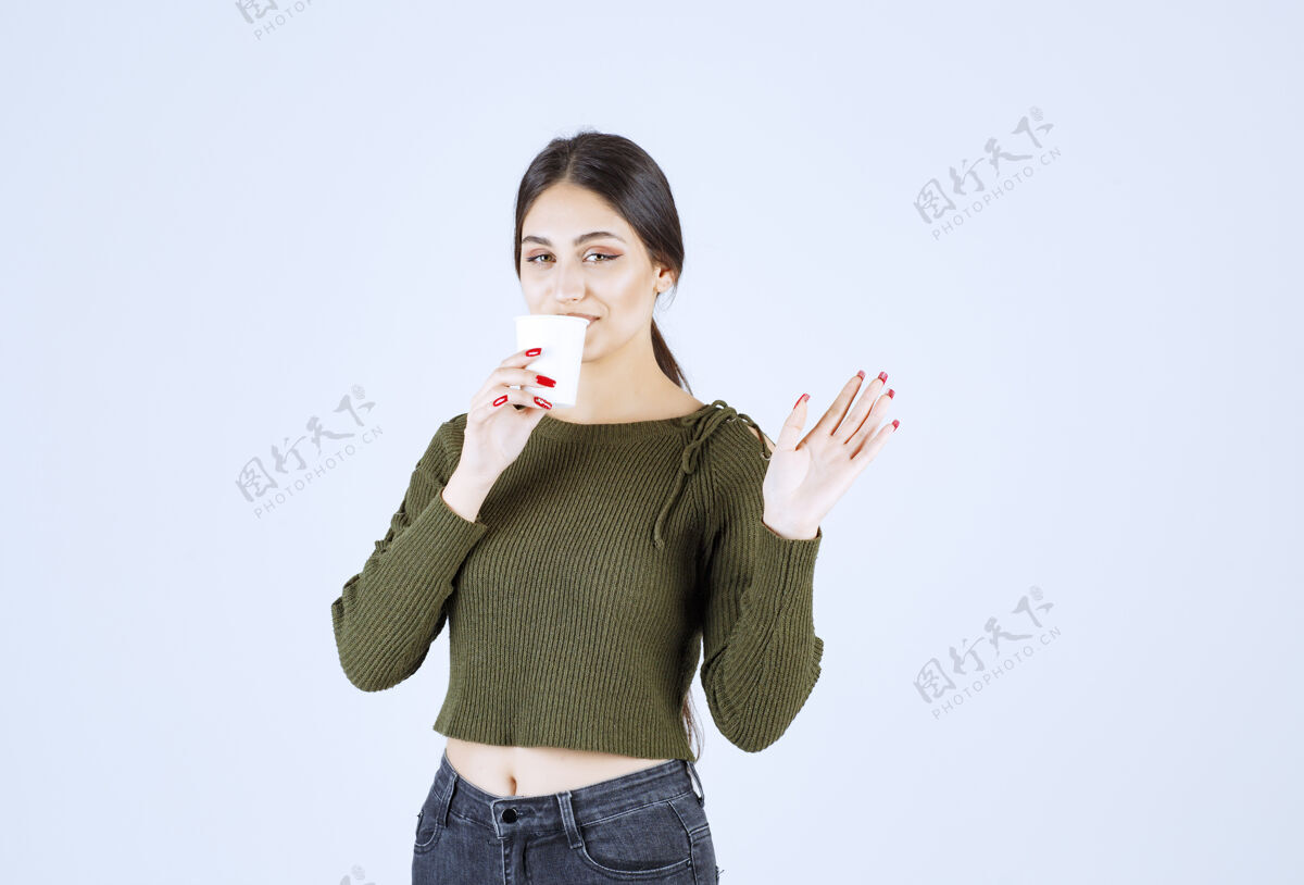 挥手一个年轻漂亮的女模特喝着塑料杯 挥舞着一只手手女性女人