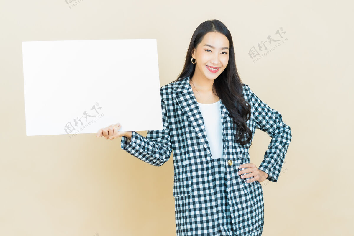 女人肖像美丽的年轻亚洲妇女与空白的白色广告牌米色休闲中国人板