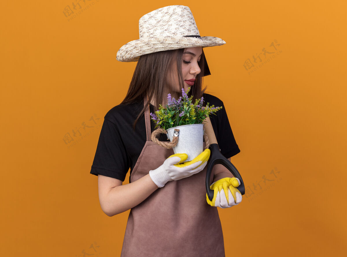 女高兴的是漂亮的白人女园丁戴着园艺帽和手套拿着花盆看着铁锹花园手握黑桃
