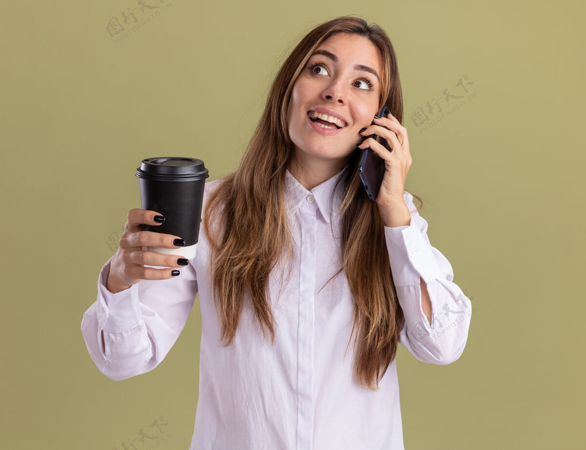 壁板兴奋的年轻漂亮的白人女孩拿着纸杯 一边看一边讲电话兴奋举行纸