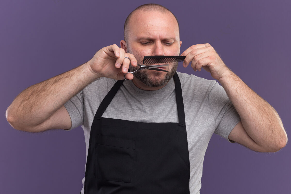 剪刀自信的中年男理发师穿着制服剪胡子用剪刀隔离在紫色的墙上立场脸感情