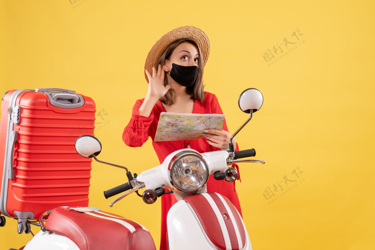 摩托车前视图戴着黑色面具的年轻女士拿着地图 听着附近有什么东西成人滑板车旅游