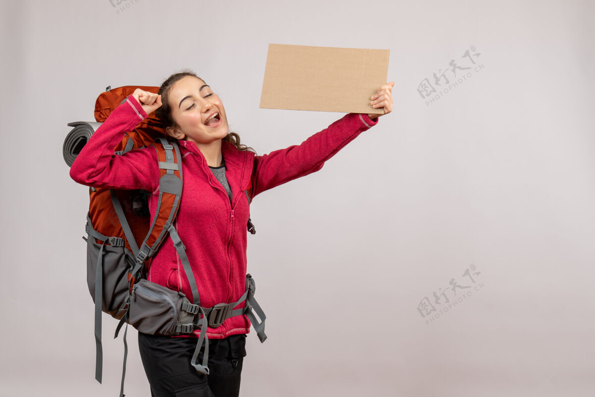 漂亮正面图：年轻的旅行者背着大背包举着纸板度假标志搭便车