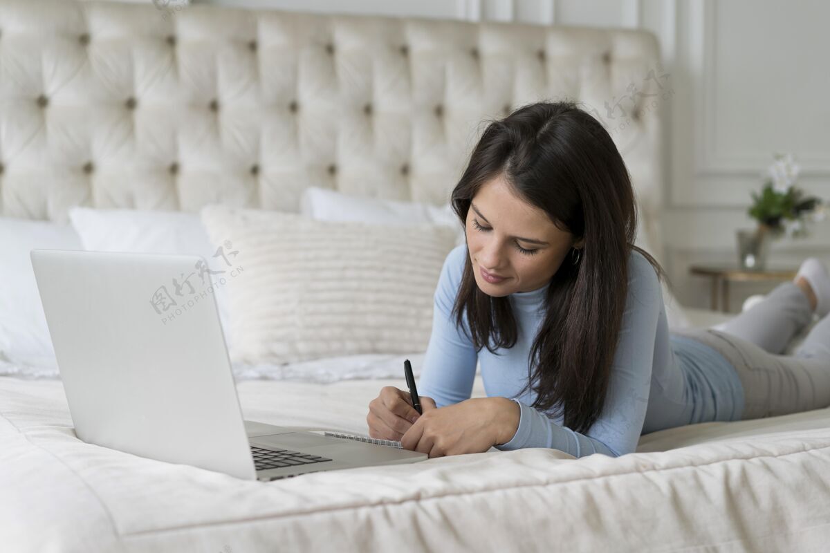 科技躺在床上用笔记本电脑打视频电话的女人科技虚拟房子