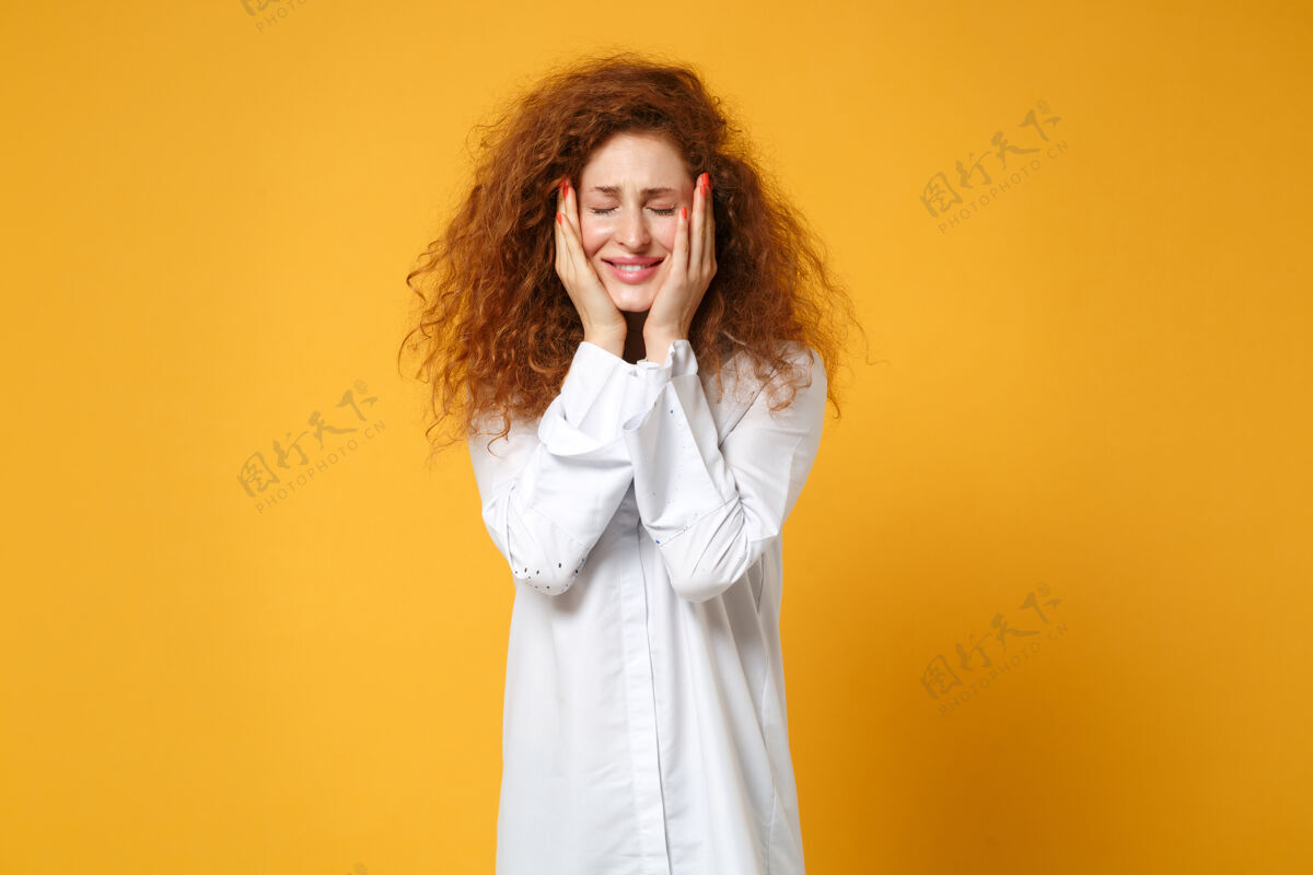 女孩微笑着的年轻红发女子穿着休闲白衬衫在黄橙色的墙上摆出孤立的姿势红发衬衫女士