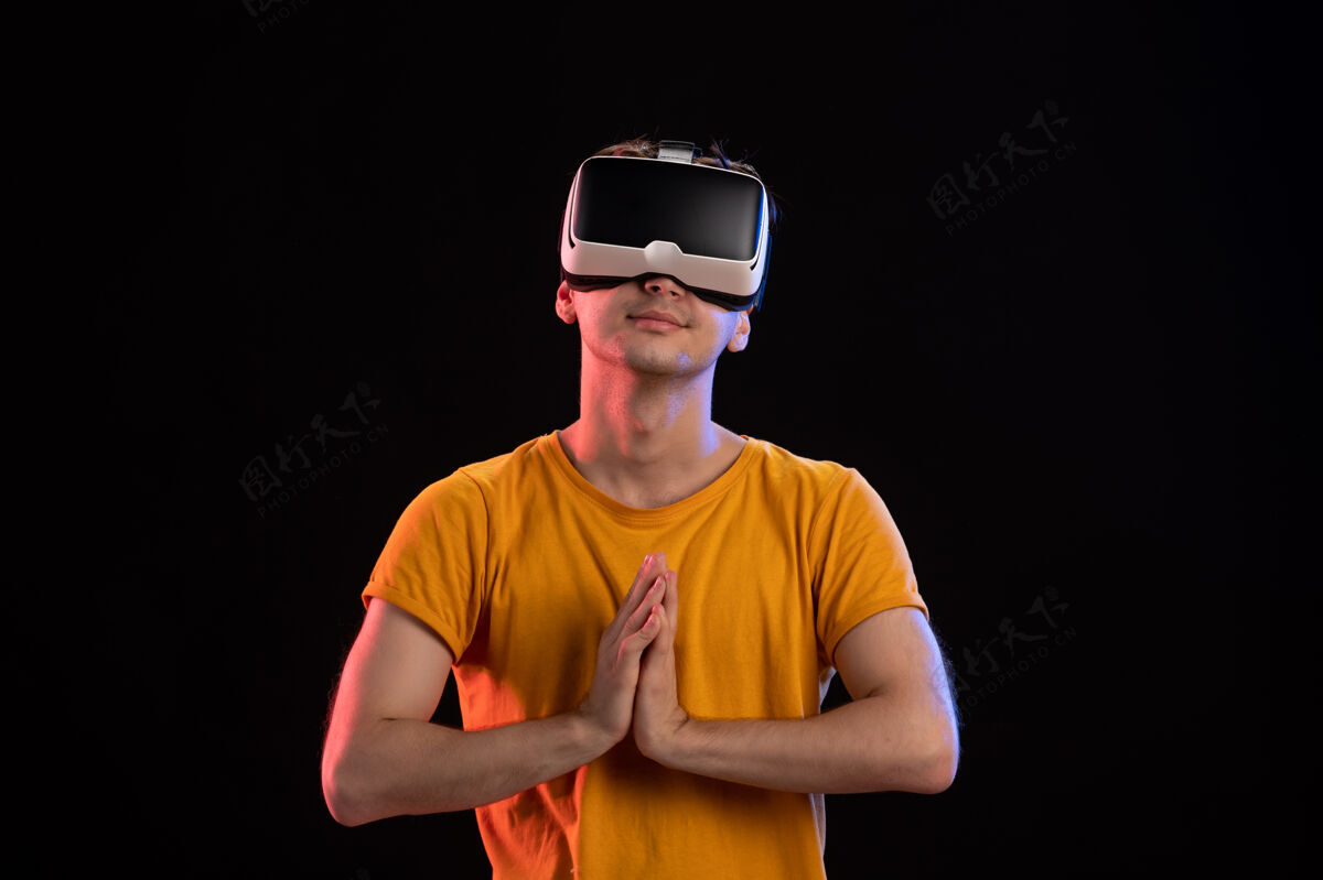 成人戴着vr耳机的年轻人在黑暗的墙壁上的正面视图人游戏虚拟现实