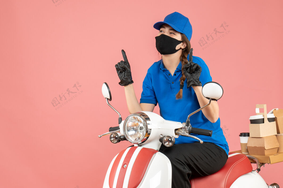 交付俯视图上的快递女孩戴着医用面罩和手套坐在滑板车上传递订单指向粉红色背景车辆粉彩医疗