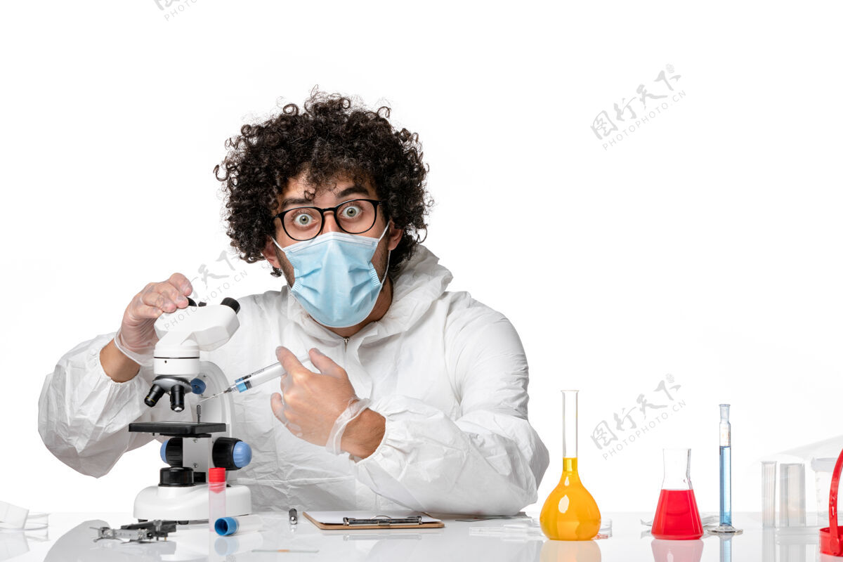工作男医生穿着防护服 戴着口罩 用显微镜在浅白上工作流行病实验室人