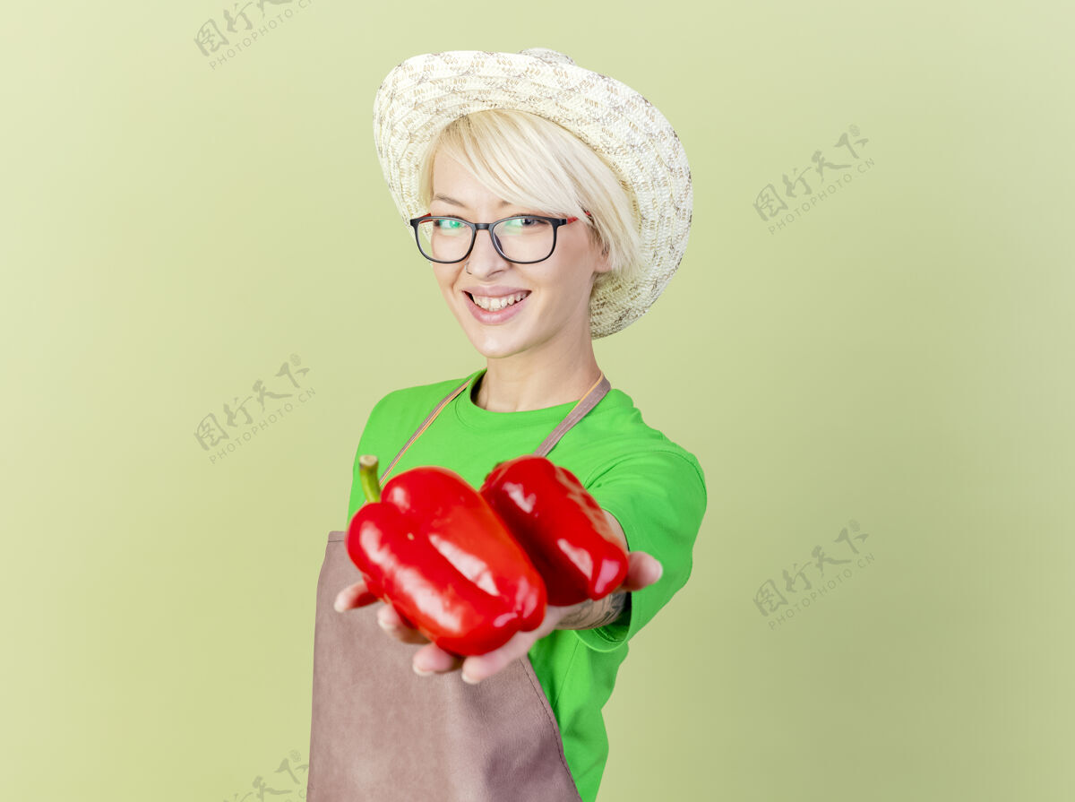 围裙一位年轻的园丁 围裙短发 戴着帽子 脸上挂着微笑的红甜椒年轻秀胡椒