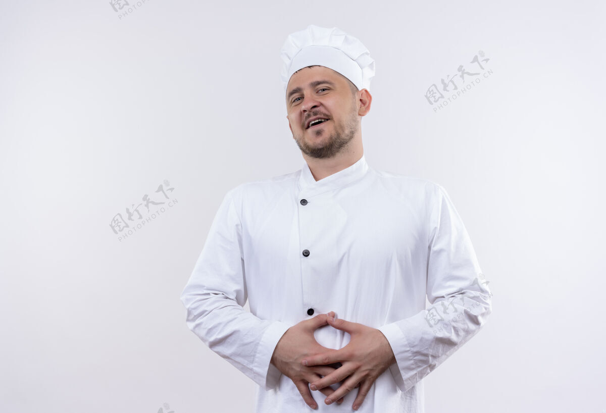 烹饪身着厨师制服的年轻帅哥厨师手放在隔离的白墙上的肚子上厨师手快乐