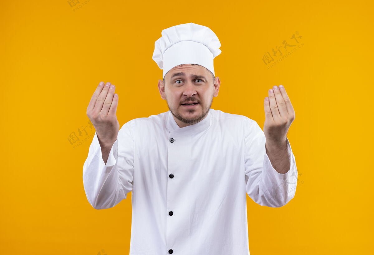 年轻年轻帅气的厨师穿着厨师制服 举起的手孤立在橙色的墙上厨艺帅气手