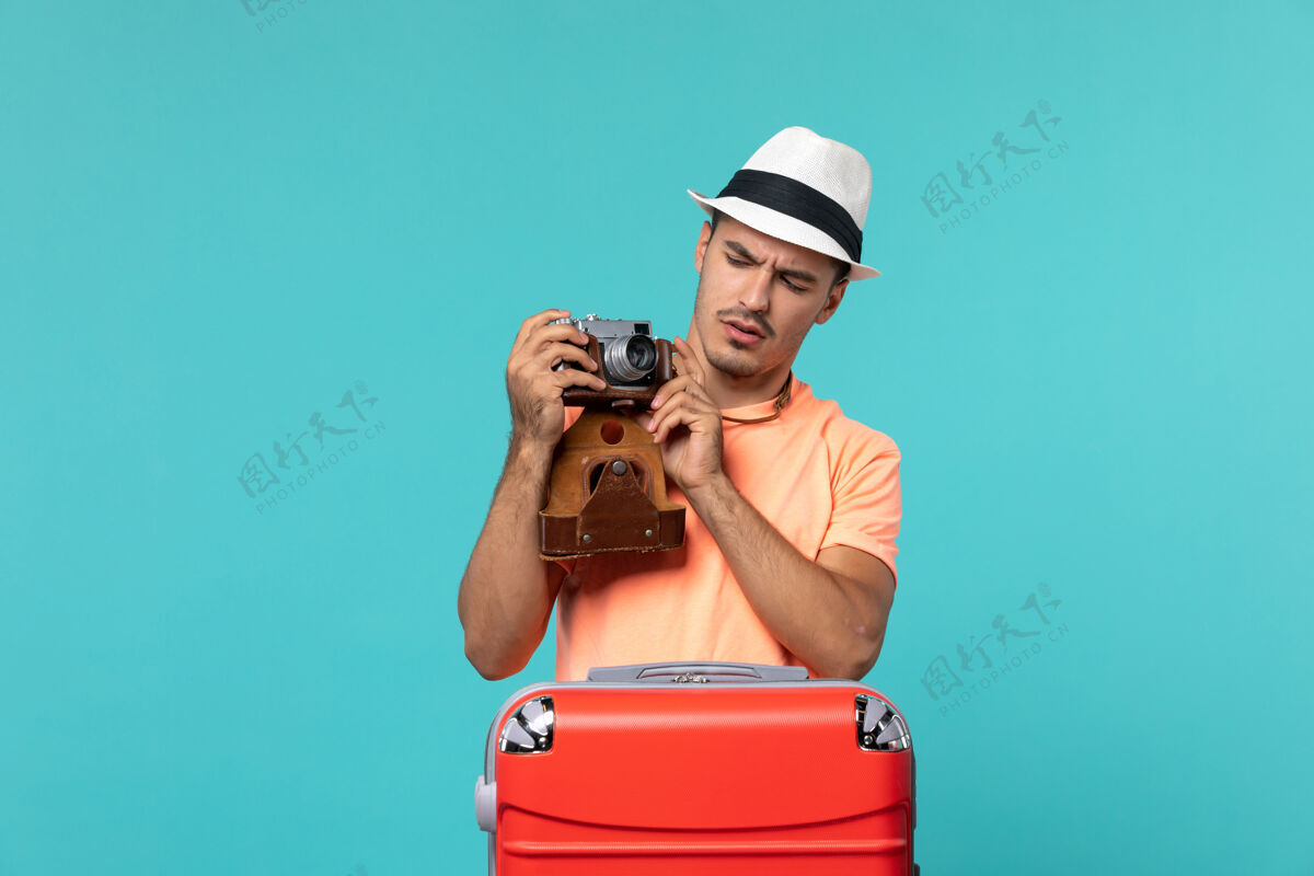 帽子带着红色手提箱和蓝色相机拍照的度假男人相机旅行包