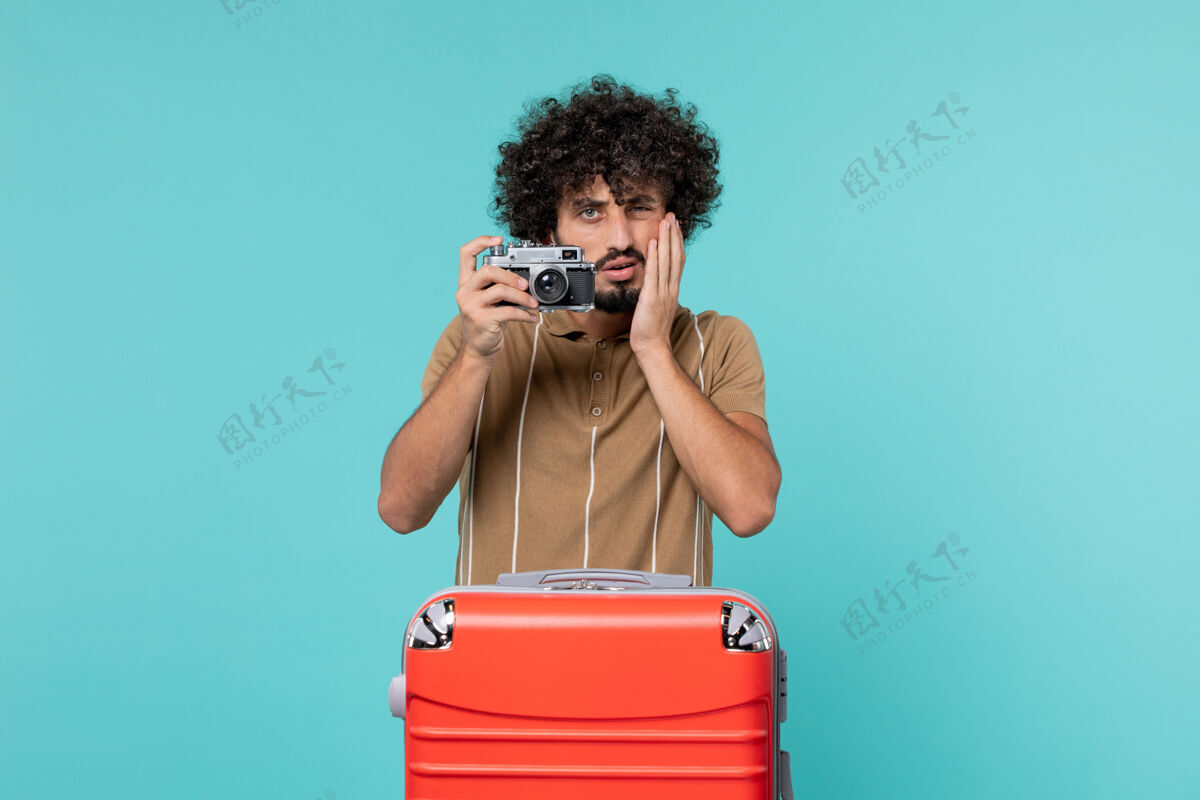 旅行带着红色手提箱的度假男人用蓝色的相机拍照包相机人