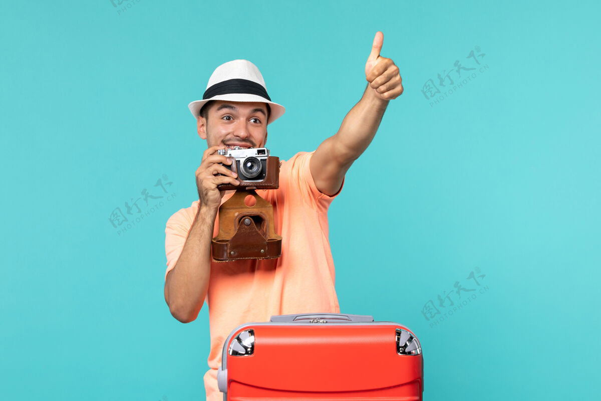 红色带着红色手提箱和蓝色相机拍照的度假男人相机男性男人
