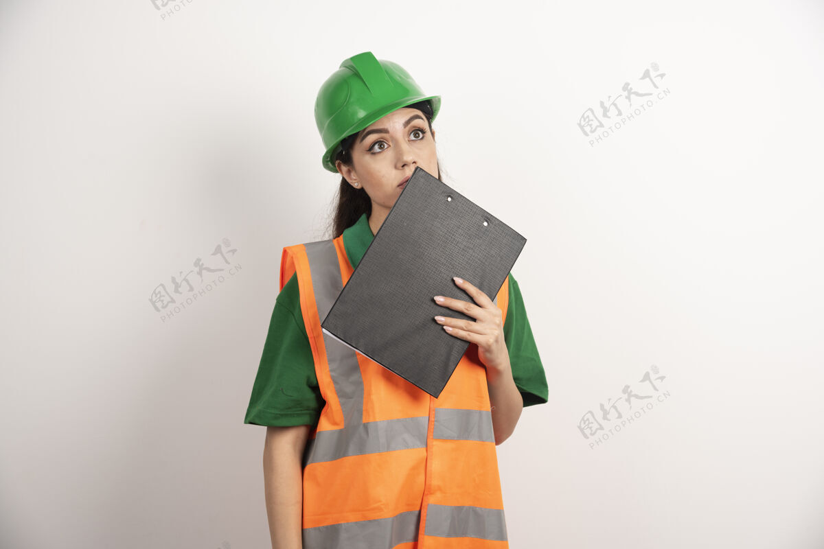 工作戴着头盔和剪贴板的年轻女工高质量的照片制服工程师工厂