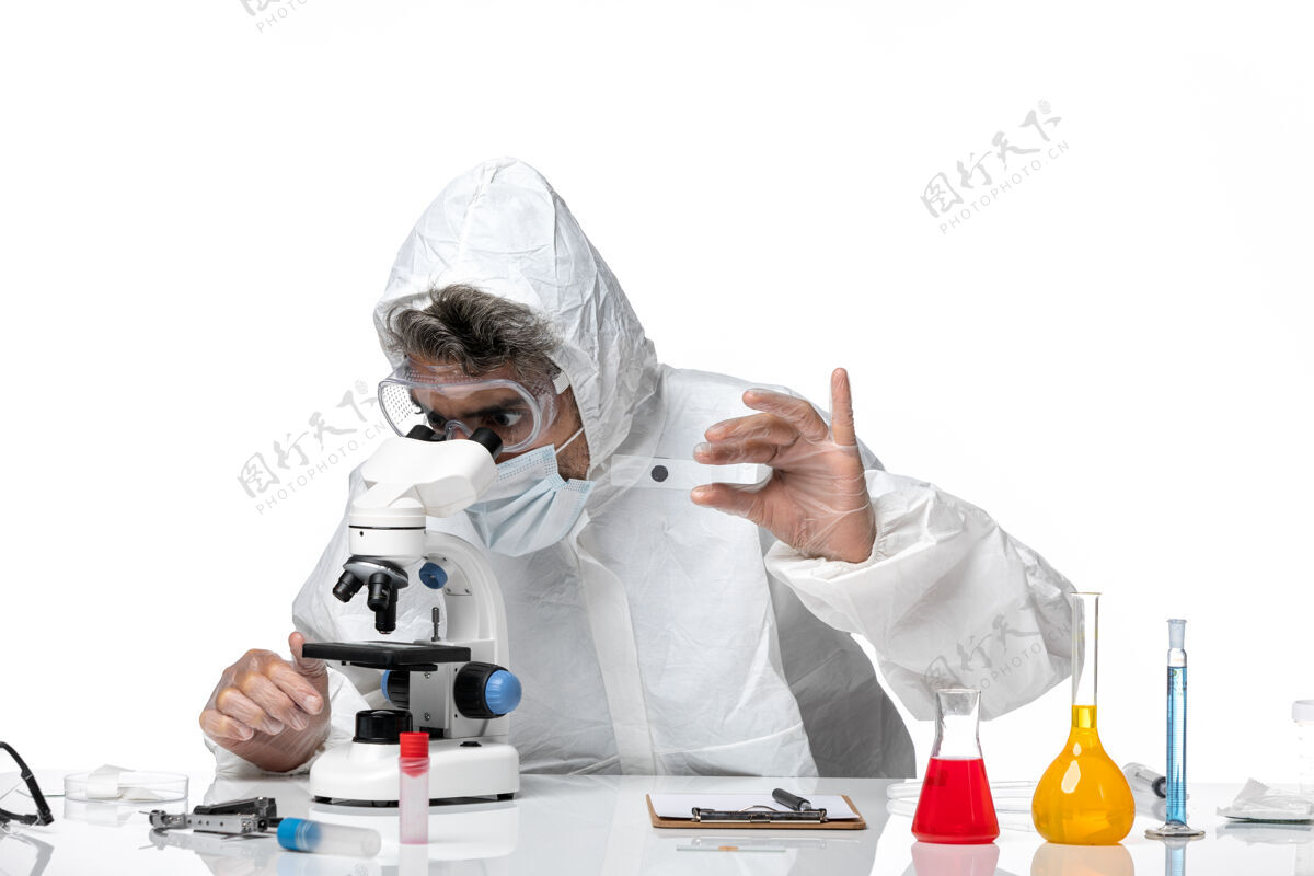 男医生男医生穿着防护服 戴着无菌口罩 用显微镜对着白色防护医生套装