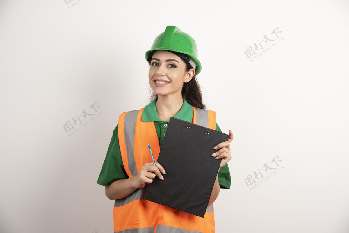 头盔微笑的女工程师拿着白色背景的剪贴板高质量的照片工作女孩安全帽