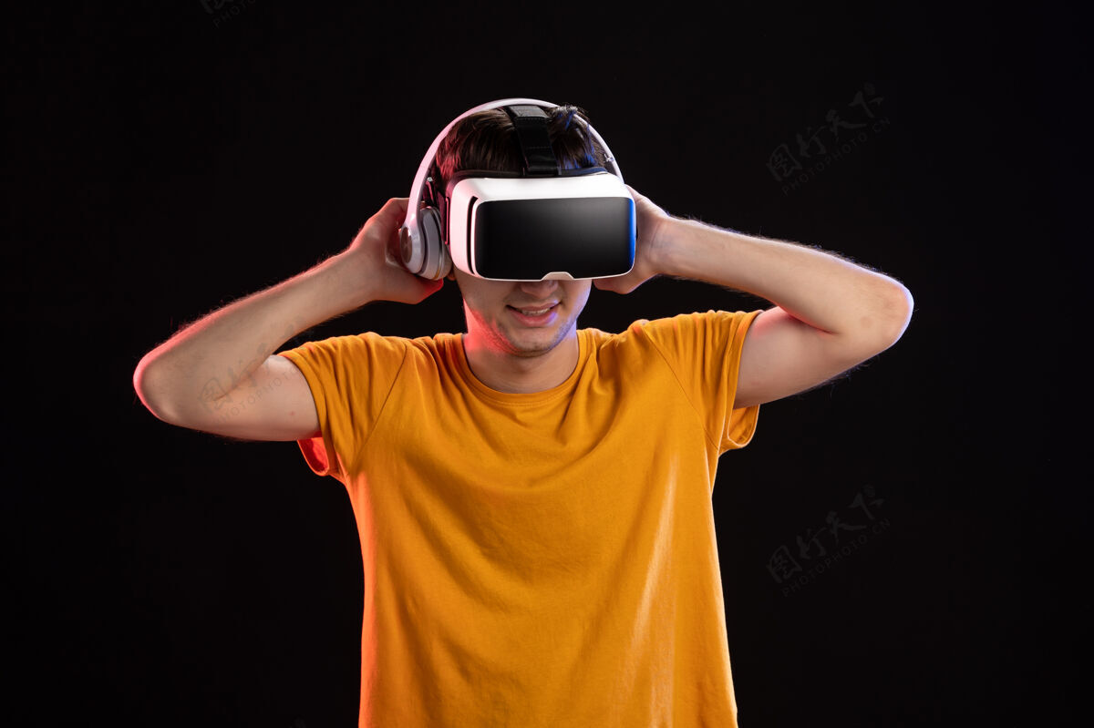 耳机在黑暗的墙上 年轻人戴着耳机玩虚拟现实的画像游戏黑暗成人
