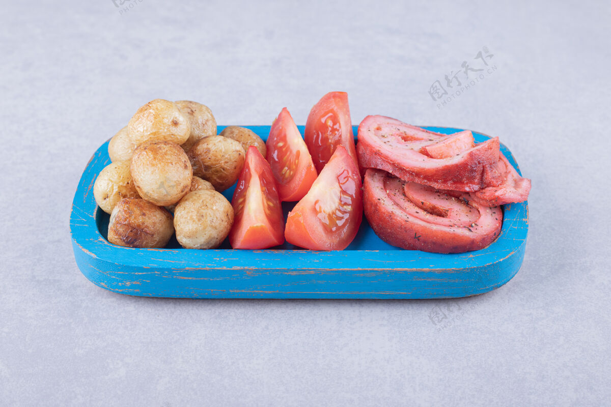 西红柿火腿卷 西红柿和炸土豆放在蓝色盘子里肉猪肉一餐