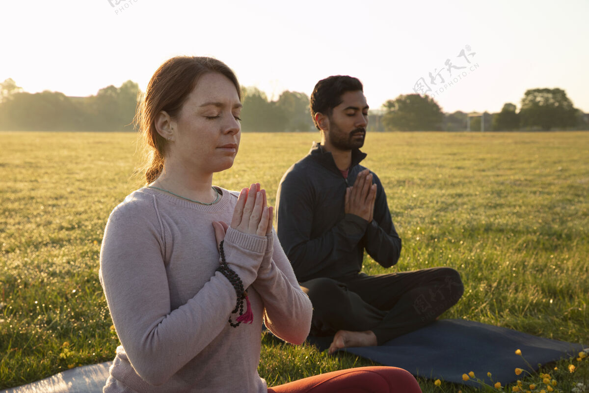 瑜伽垫男人和女人在户外冥想的侧视图反射禅宗男人