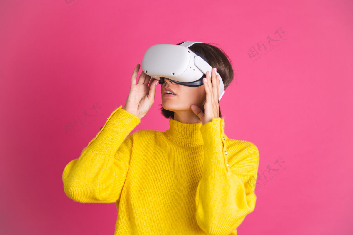 科技穿着亮黄色毛衣的美女戴着粉色的虚拟现实眼镜开心兴奋喜出望外的触摸空气现实衬衫Omg