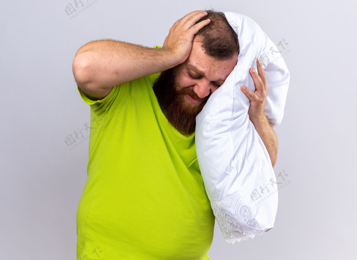 男人穿着黄色马球衫 留着不健康的胡须 站在白墙上抱枕 头痛得厉害头痛不健康感觉