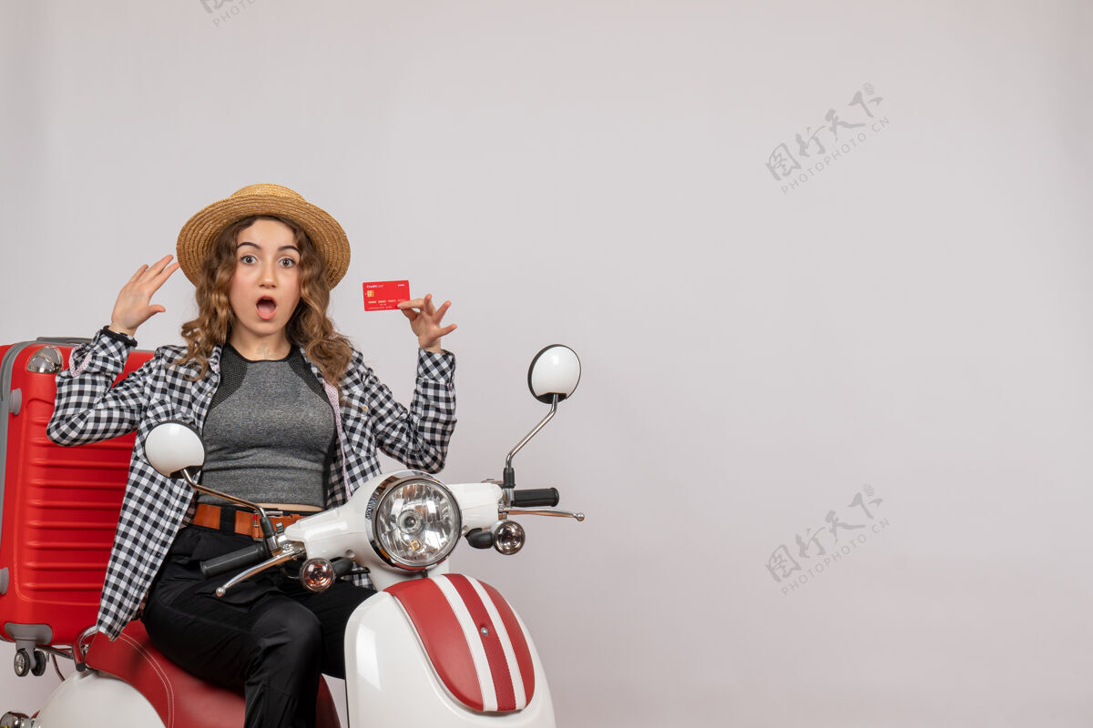 灰色坐在轻便摩托车上拿着灰色隔离牌的年轻女子惊诧不已人成人坐着