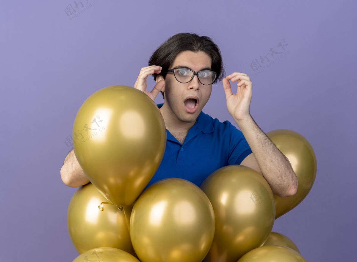 光学一个戴眼镜的白人帅哥站在氦气球旁看着相机氦站紫色