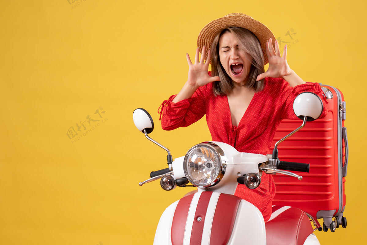 漂亮女孩骑着轻便摩托车 带着红色手提箱的漂亮女孩在喊成人车辆人