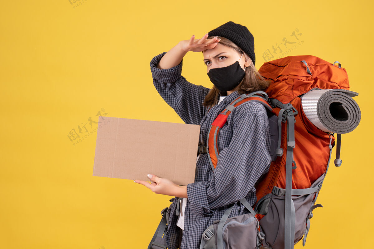 背包带着黑色面具和背包拿着纸板的旅行女孩面具人成人
