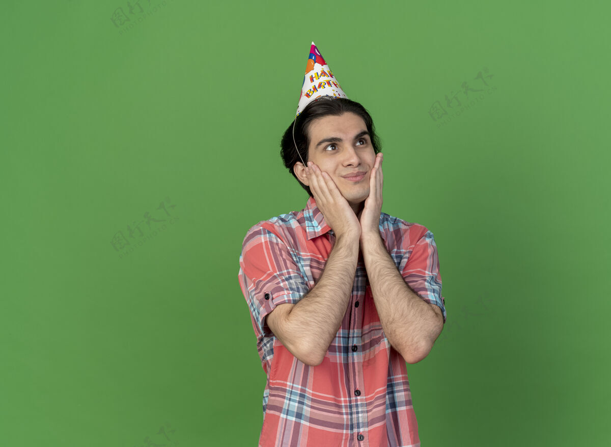 绿色高兴的白种帅哥戴着生日帽把手放在脸上看着身边空间帽子脸