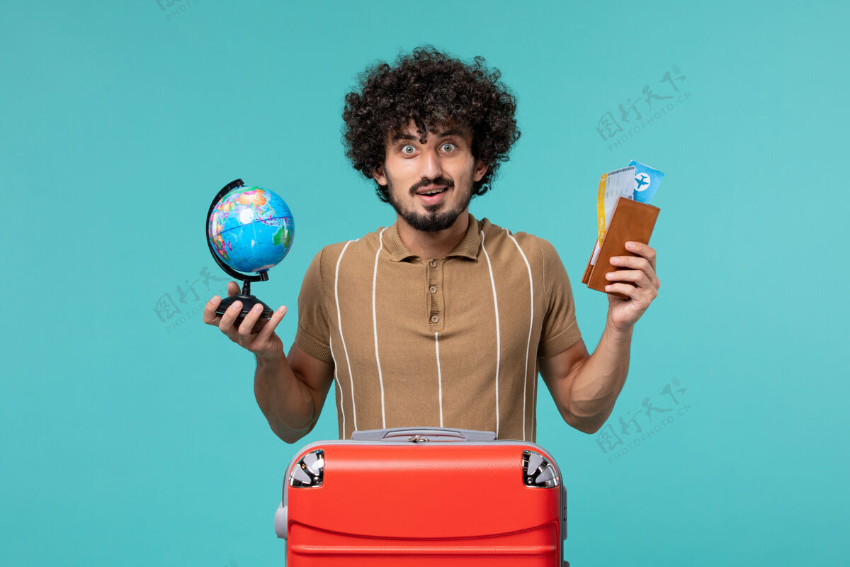 男人前视图中的度假男子拿着地球仪和蓝色的机票地球仪蓝色票