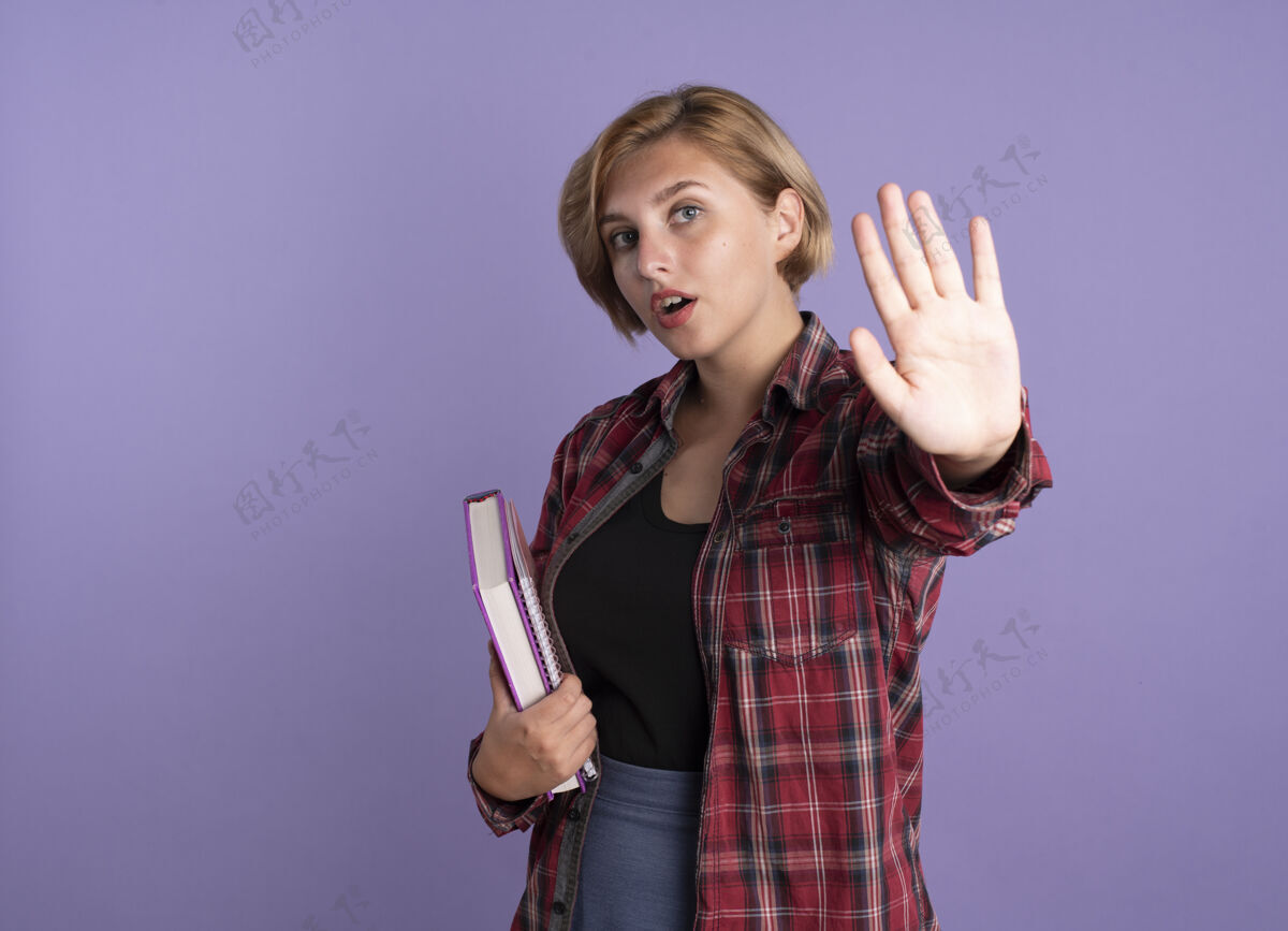 年轻自信的年轻斯拉夫学生女孩拿着书和笔记本手势停止手势笔记本女孩举行