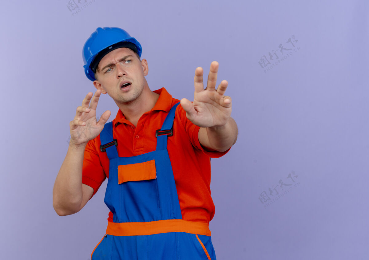 手看着身边迷茫的年轻男建筑工人穿着制服和安全帽伸出双手男性年轻紫色