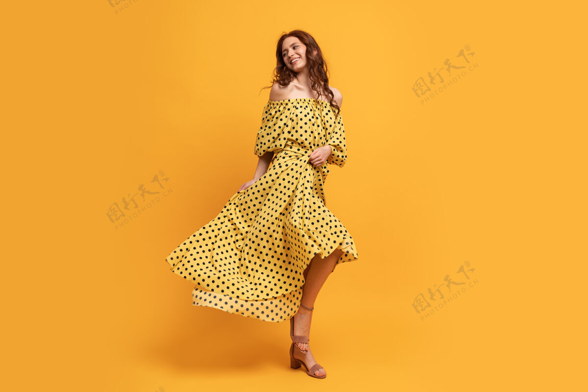 喜悦穿着黄色连衣裙的红发美女在黄色的床上摆姿势夏天的心情乐趣裙子衣服