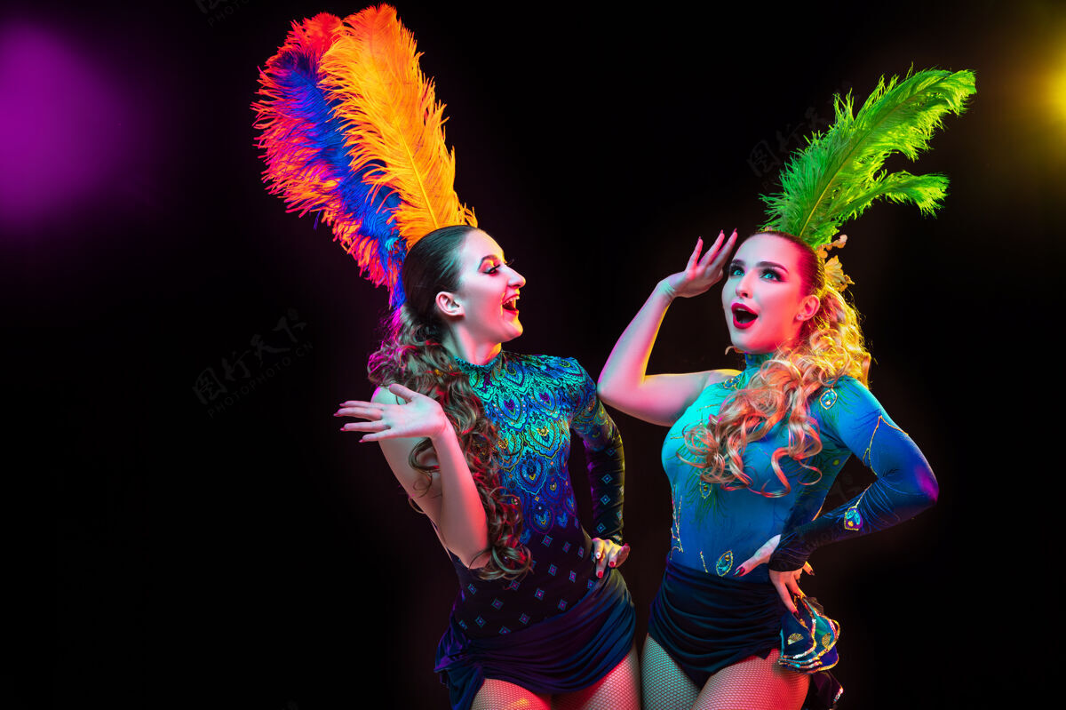 意大利美丽的年轻女子在狂欢节 时尚的化装服装与羽毛在霓虹灯下的黑色墙壁河流年服装