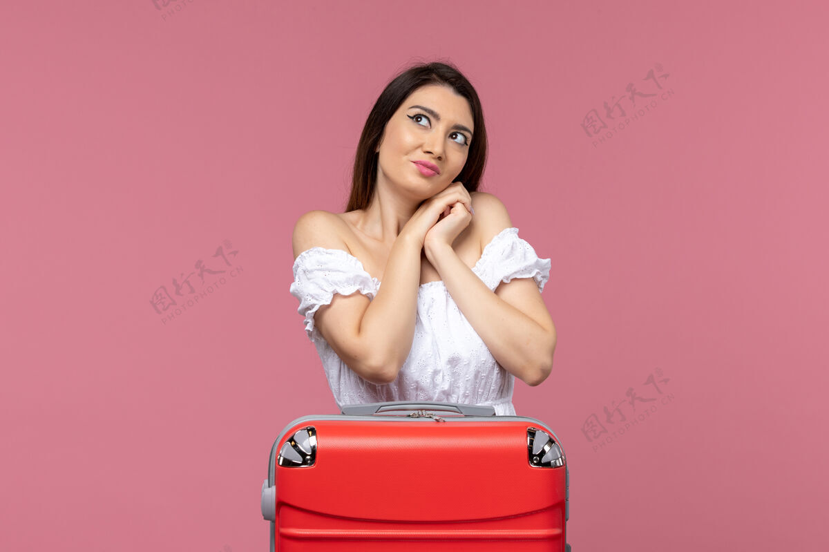 人正面图：年轻女性带着她的包准备度假 背景是粉色的出国海游漂亮旅行年轻女性