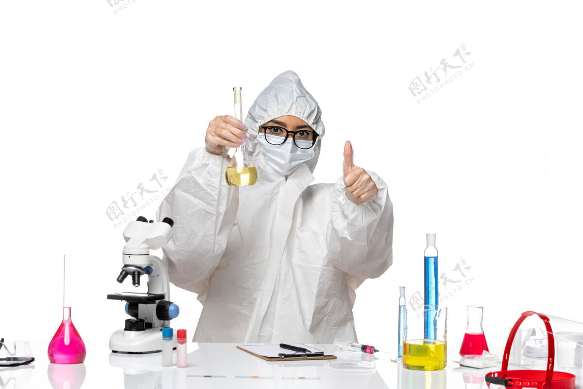 保温瓶正面图身穿特殊防护服的年轻女化学家拿着装有淡白色背景溶液的烧瓶实验室病毒化学防护溶液实验室外套