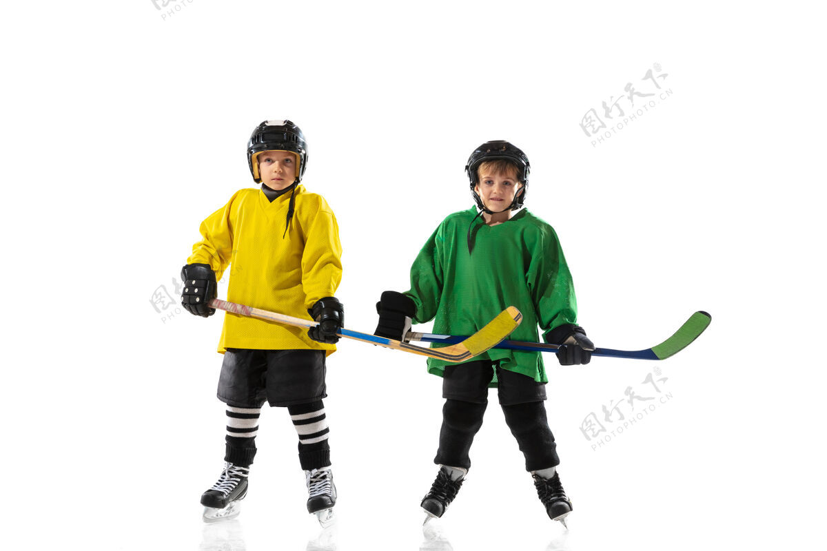 运动员冰球场上拿着棍子的小冰球运动员和白色的工作室墙棍棒动作运动服
